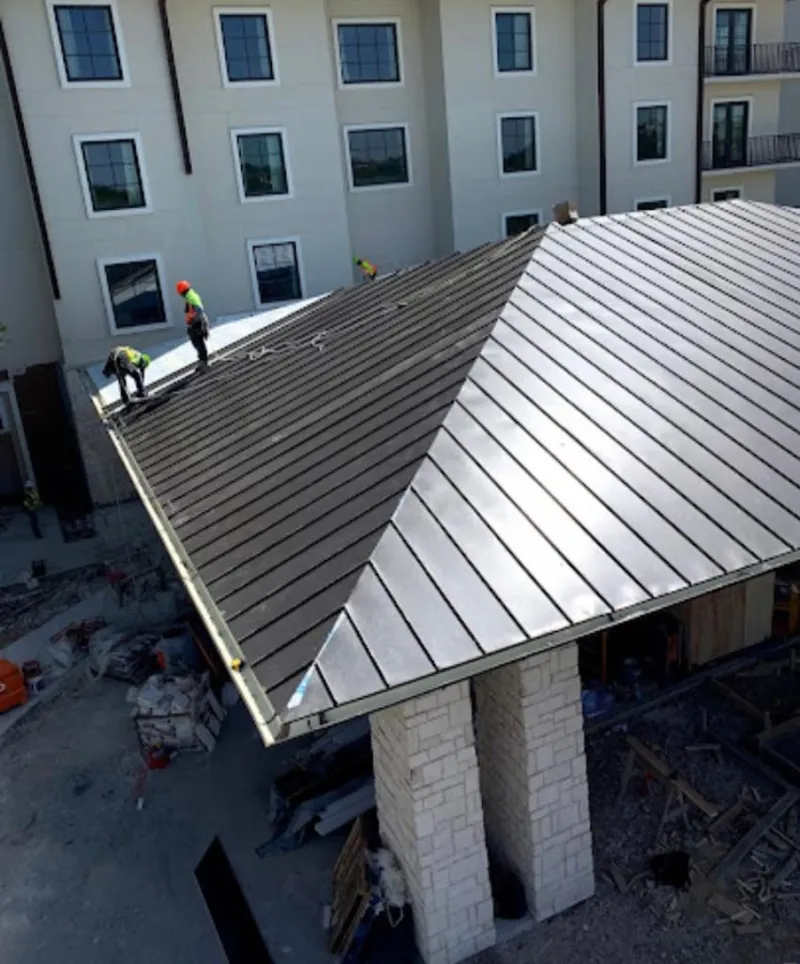 Crew installing standing seam metal roof panels on a commercial project in Little River